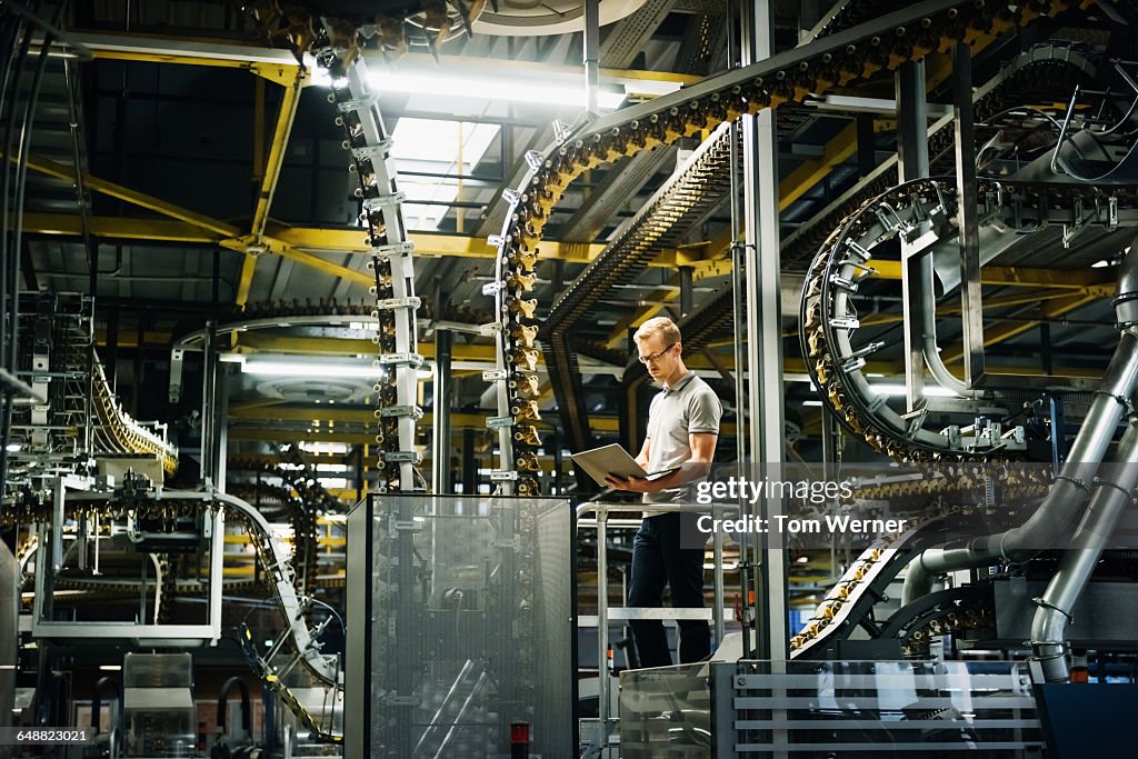 Engineer with laptop in a factory between machines