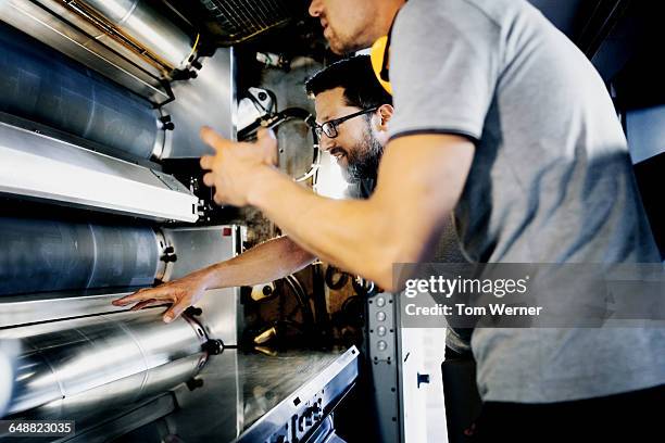 two engineers checking a printing machine - drukkerij stockfoto's en -beelden