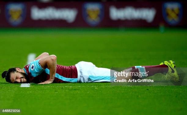 Andy Carroll of West Ham United winces as he lays prone during the Premier League match between West Ham United and Chelsea at London Stadium on...