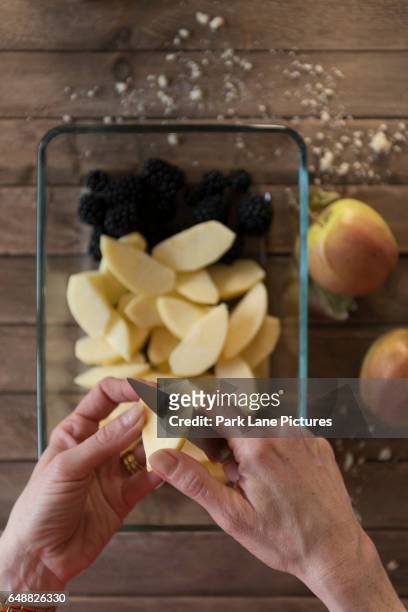 a woman prepares a fruit crumble pudding. slicing apples. - pudding crumble photos et images de collection