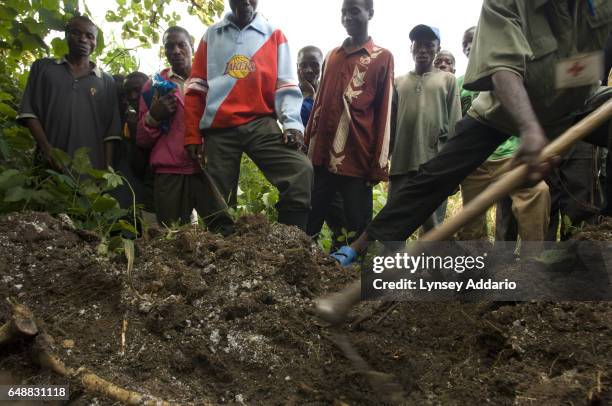 Congolese villagers and soldiers with the Rwandan-led Hutu militia known as the Democratic Liberation Forces of Rwanda, FDLR, stand over a mass grave...