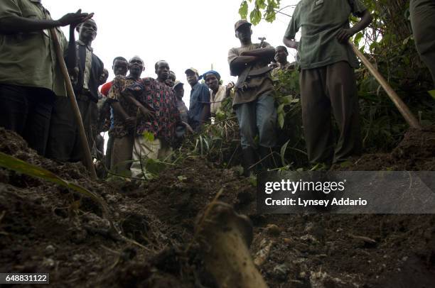 Congolese villagers and soldiers with the Rwandan-led Hutu militia known as the Democratic Liberation Forces of Rwanda, FDLR, stand over a mass grave...