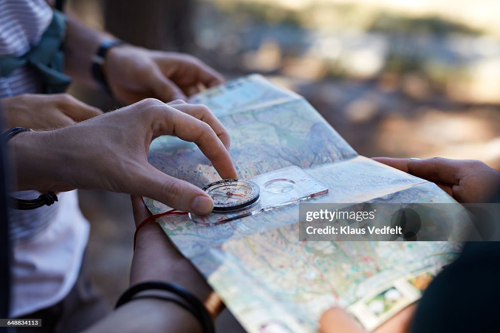 Close-up of hands holding compass & map