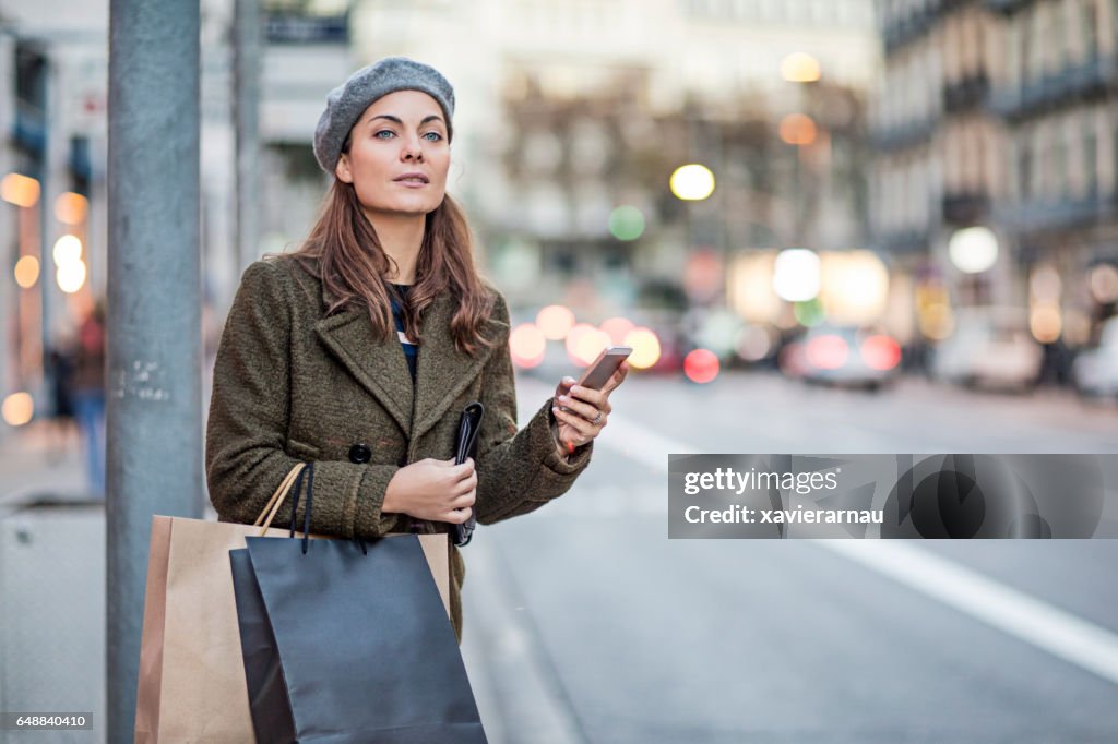 Woman with smart phone and shopping bags at street