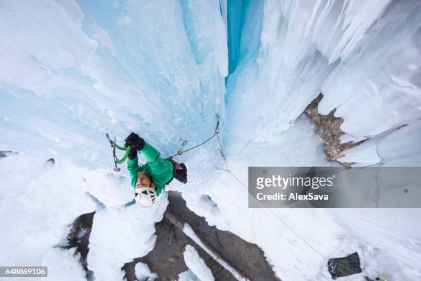 mannelijke alpinist ijsklimmen op een bevroren waterval - frozen waterfall stockfoto's en -beelden