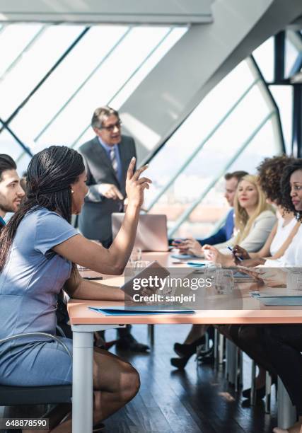 businesswoman raising hand in the middle of a meeting - participant stock pictures, royalty-free photos & images