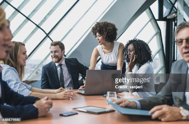 mensen uit het bedrijfsleven hebben een vergadering in de bestuurskamer - multi ethnic business people having discussion at table in board room stockfoto's en -beelden