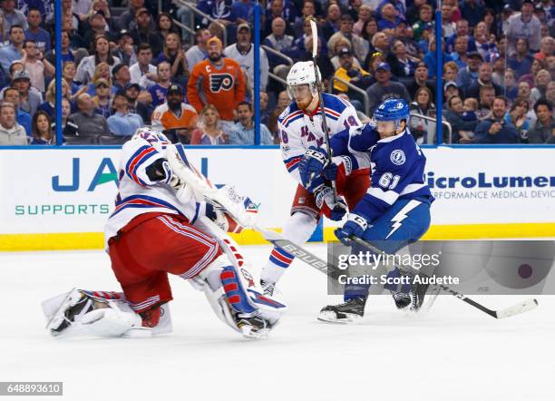 Goalie Antti Raanta of the New York Rangers clears the puck as teammate Marc Staal battles against Gabriel Dumont of the Tampa Bay Lightning during...