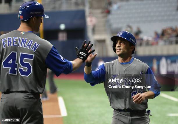 Outfielder Sam Fuld of Israel high fives with Nate Freiman after scoring a run in the top of the first inning during the World Baseball Classic Pool...