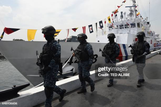 Members of Philippine coast guard anti-terrorism unit stand next to the newly commissioned coast guard's Multi-Role Response Vessel BRP Malapascua...