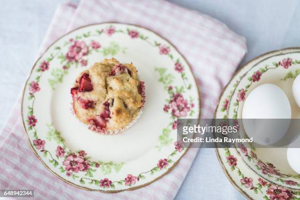 top view of a strawberry muffin in a plat and eggs behind - muffin top stock-fotos und bilder