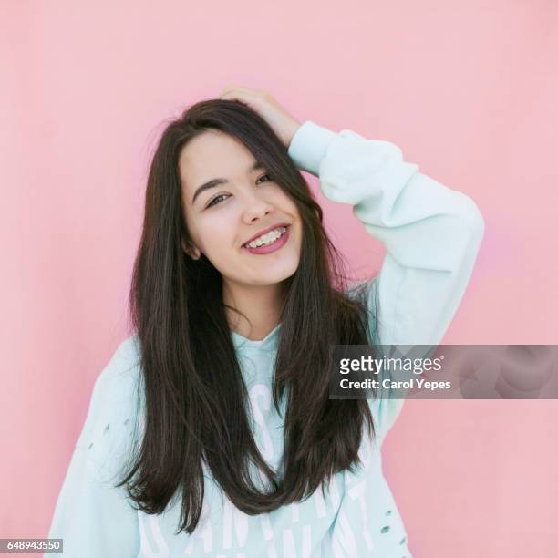 happy brunette young girl teenager in pink background - brunette smiling stock-fotos und bilder