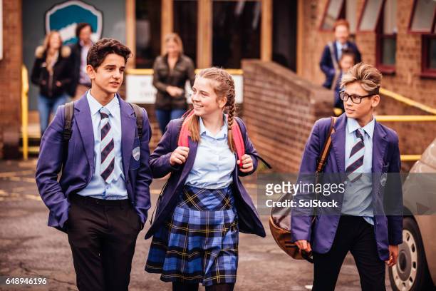 school friends leaving school for the day - school uniform stock pictures, royalty-free photos & images