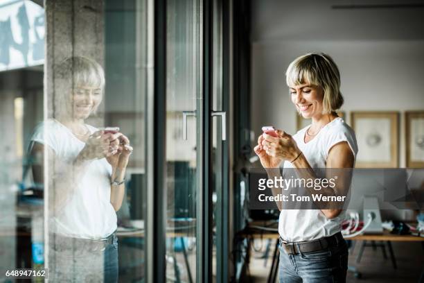 portrait of modern businesswoman with smart phone in her office - lässige kleidung stock-fotos und bilder