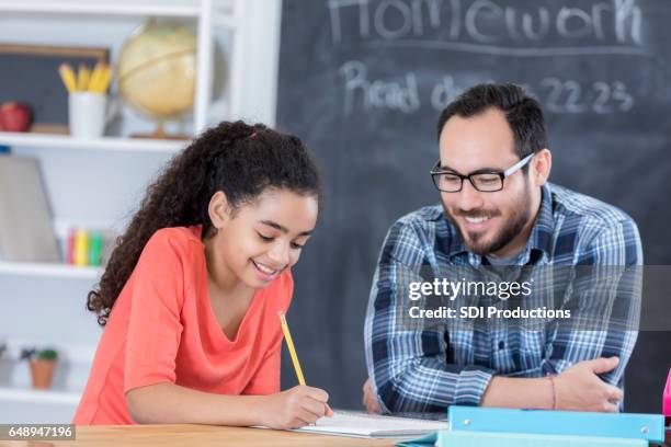 vertrouwen middelste schoolmeisje werkt op toewijzing - two female teachers blackboard stockfoto's en -beelden