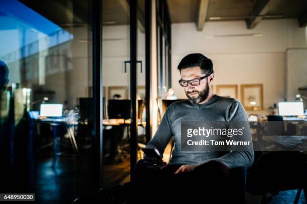 casual businessman working late on a laptop computer - business smartphone stock-fotos und bilder