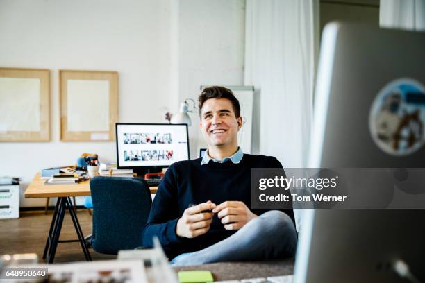 portrait of a young casual businessman sitting on his desk - entrepreneur stockfoto's en -beelden