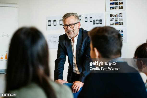 mature businessman speaking in an informal meeting - directivos fotografías e imágenes de stock