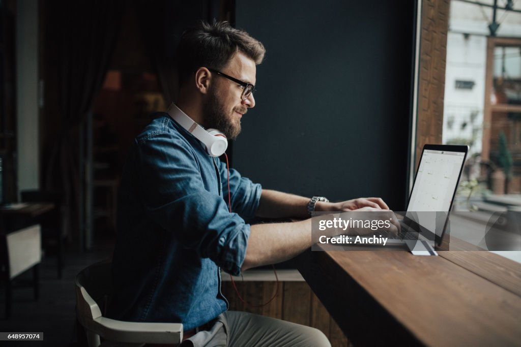 Bearded graphic designer checking schedule on laptop