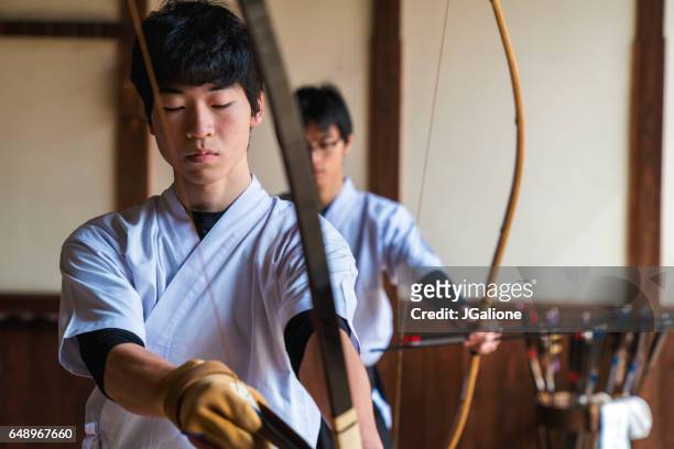 young archer nocking an arrow - japanese martial arts stock pictures, royalty-free photos & images