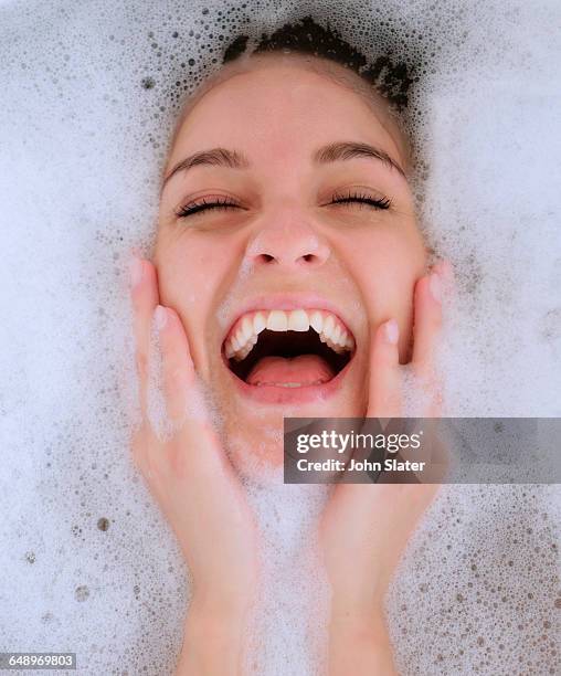 young woman laughing in bubble bath - woman bath tub wet hair stock pictures, royalty-free photos & images