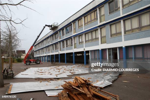 Employees clear metal roofing sheets from the courtyard of the Therese Simonet elementary school on March 7, 2017 in Brive-la-Gaillarde, a day after...