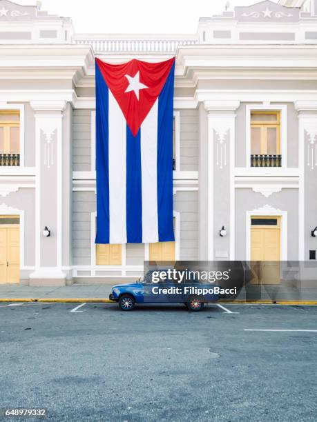 oldtimers onder een grote vlag van cuba in cienfuegos - cienfuegos stockfoto's en -beelden