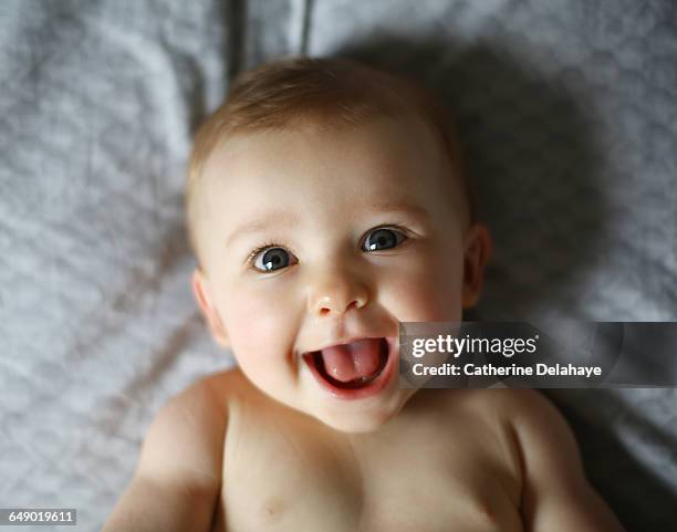 a naked 7 months old baby laying on a bed - baby girl fotografías e imágenes de stock