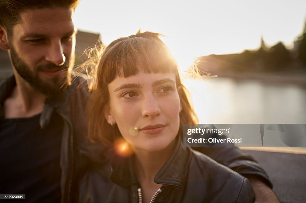 Young couple in backlight by the riverside