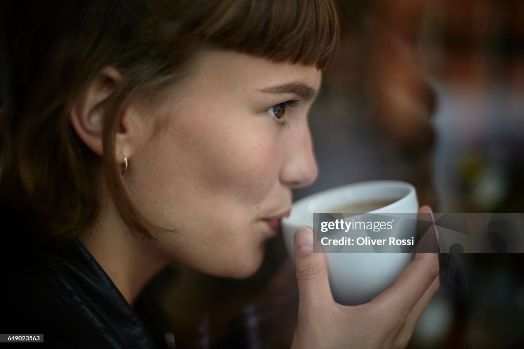 Young woman drinking cup of coffee