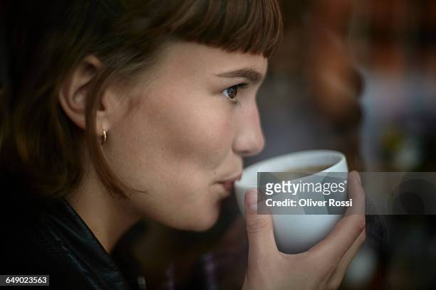 young woman drinking cup of coffee - women drinking coffee stock-fotos und bilder