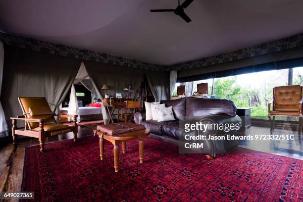 Leather sofa and antique furniture in the sitting room of a luxurious tented safari camp.