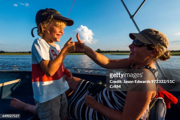 Mother and son playing thumb fighting games on an African safari boat.