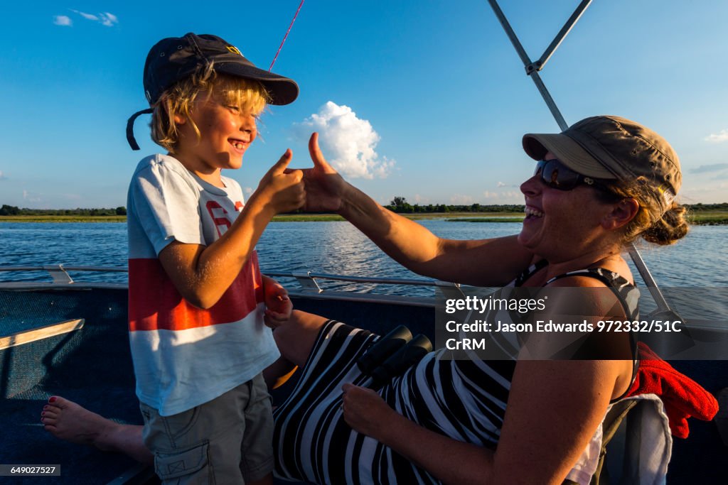 A mother and son playing thumb fighting games on an African safari boat.
