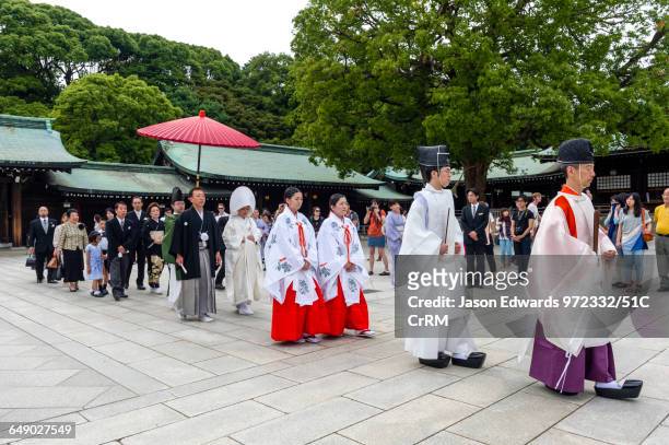 a traditional shinto wedding procession slowing parading through a temple. - shinto photos et images de collection