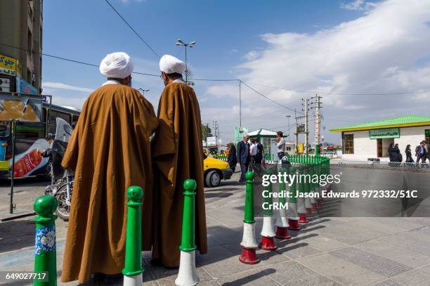 a pair of clergyman wearing turbans and woven cloaks in deep conversation outside a shrine. - iranian mullahs stock pictures, royalty-free photos & images
