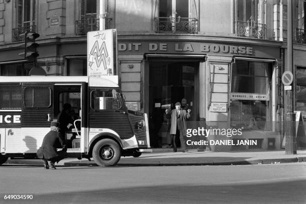Policemen stand guard in front of the Credit de la Bourse bank as gangsters leave with hostages during a robbery, on January 31, 1974 on Place de la...
