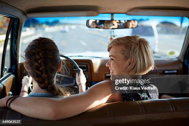 girls lauging together while driving car - front passenger seat stock-fotos und bilder