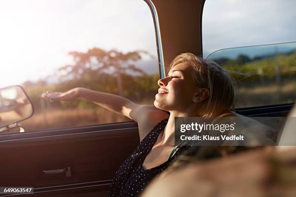 woman relaxing with arm out of window of car - car passenger side stock pictures, royalty-free photos & images