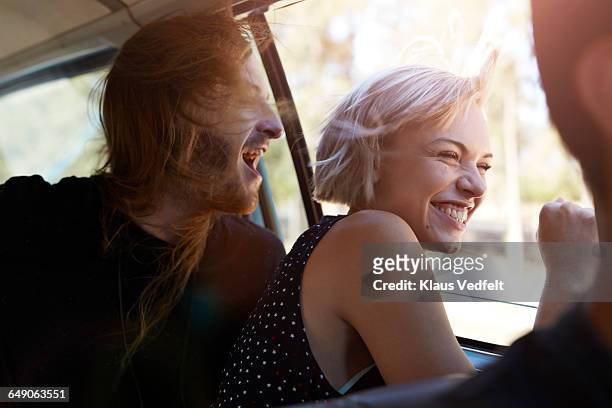 friends laughing & looking out of window of car - haare mann stock-fotos und bilder