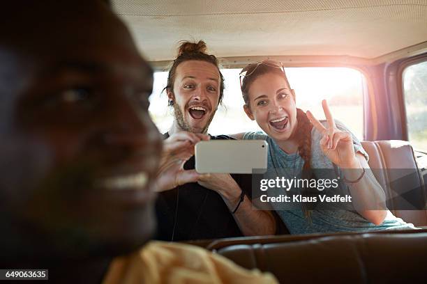 couple making selfie inside car - guy in car seat stockfoto's en -beelden