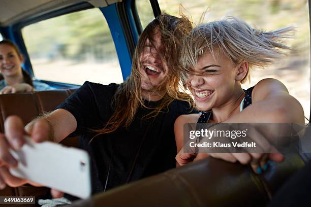 couple making selfie inside car with open window - open hair selfie stock pictures, royalty-free photos & images