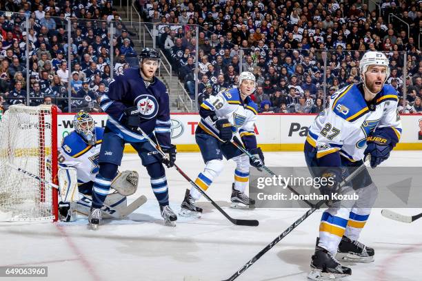 Adam Lowry of the Winnipeg Jets stands among Carter Hutton, Jay Bouwmeester and Alex Pietrangelo of the St. Louis Blues as they keep an eye on the...