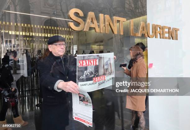 An activist of Effronte-e-s feminist movement puts a placard reading "sexist" in a Yves Saint-Laurent shop in Paris on March 7, 2017 during a...