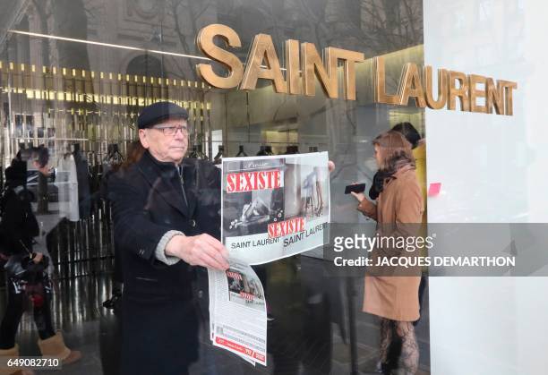 An activist of Effronte-e-s feminist movement puts a placard reading "sexist" in a Yves Saint-Laurent shop in Paris on March 7, 2017 during a...