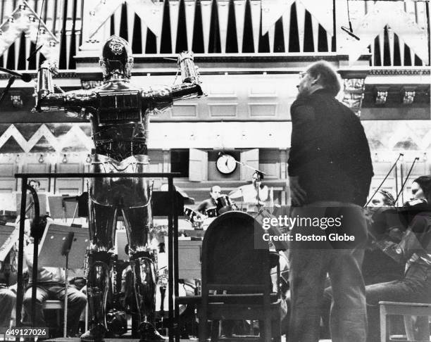 New Boston Pops conductor John Williams looks on as Star Wars character C3PO conducts the Pops during a rehearsal in Boston on April 29, 1980.