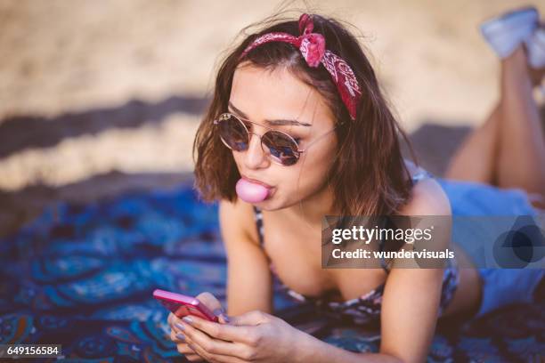 young beautiful woman texting and blowing a bubble gum - bubble gum stock pictures, royalty-free photos & images