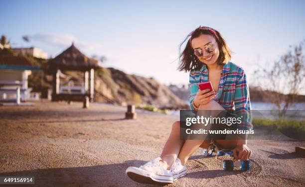 teenager mädchen skateboarder mit smartphone direkt am meer - hispanic man on beach stock-fotos und bilder