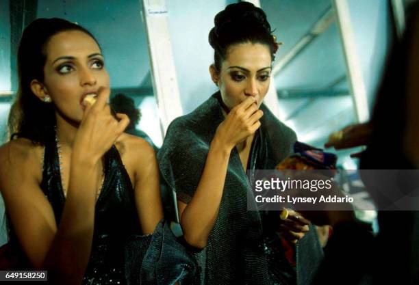 Two contestants who were just cut from one of the final rounds of the Miss India Beauty Pageant eat snacks while consoling themselves backstage at...