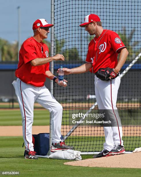 Pitching Coach Mike Maddux talks to Max Scherzer of the Washington Nationals during a morning workout prior to the spring training game against the...